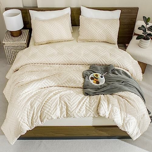 Cozy bed with beige comforter, pillows, and a tray with breakfast.