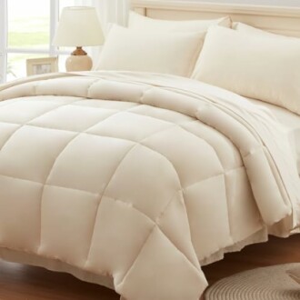 Beige comforter and pillows on a bed in a bright room.