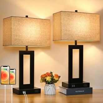 Two modern table lamps with USB ports and a small flower vase on a table.