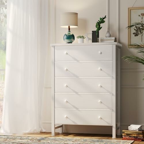 White dresser with a lamp and plant in a bright room