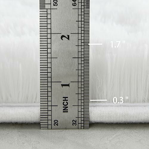 Ruler measuring thickness of white rug.